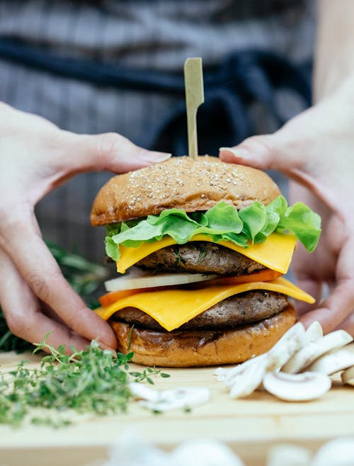 Free Faceless cook with appetizing cheeseburger in kitchen Stock Photo