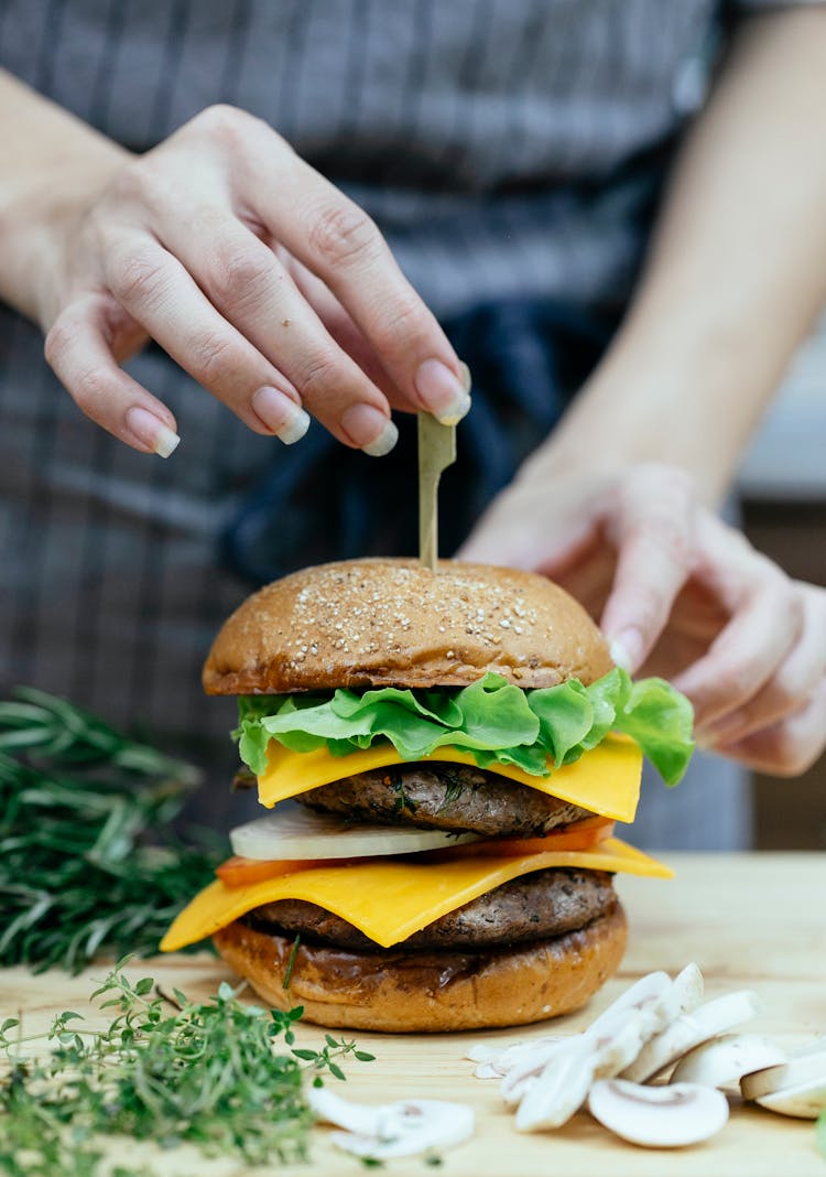 Faceless Chef Inserting Skewer Into Double Cheeseburger At Home