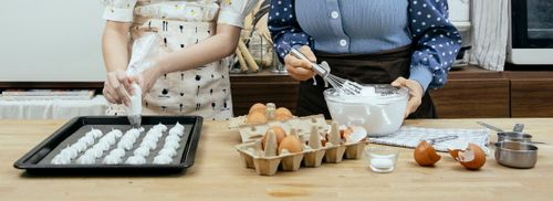 Free Crop anonymous woman with teen preparing mixture from egg whites for sweet pastries at table in house Stock Photo