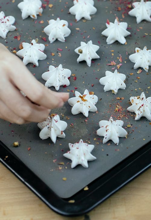 Crop chef sprinkling meringue with spices in kitchen