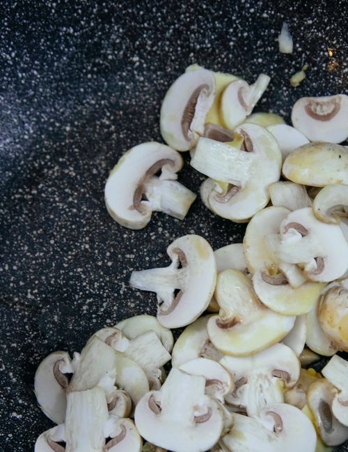 Free Top view of fresh thin mushroom slices with oil in frying pan with non stick coating Stock Photo