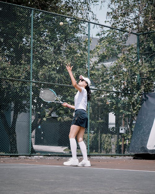 Photo of a Woman in a White Shirt Playing Tennis