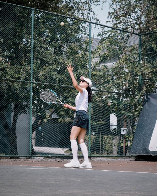 Free A woman practicing tennis outdoors, preparing to serve on a sunny day. Stock Photo