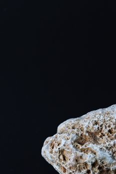 Detailed close-up of a textured stone with copyspace on a black background.
