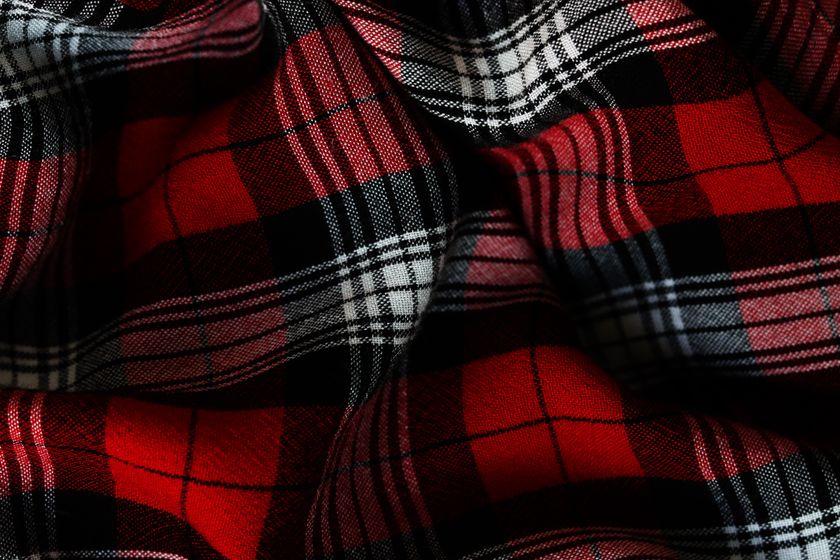 Close-up of a soft red and black check cloth in folds, the napped surface visible over the check.