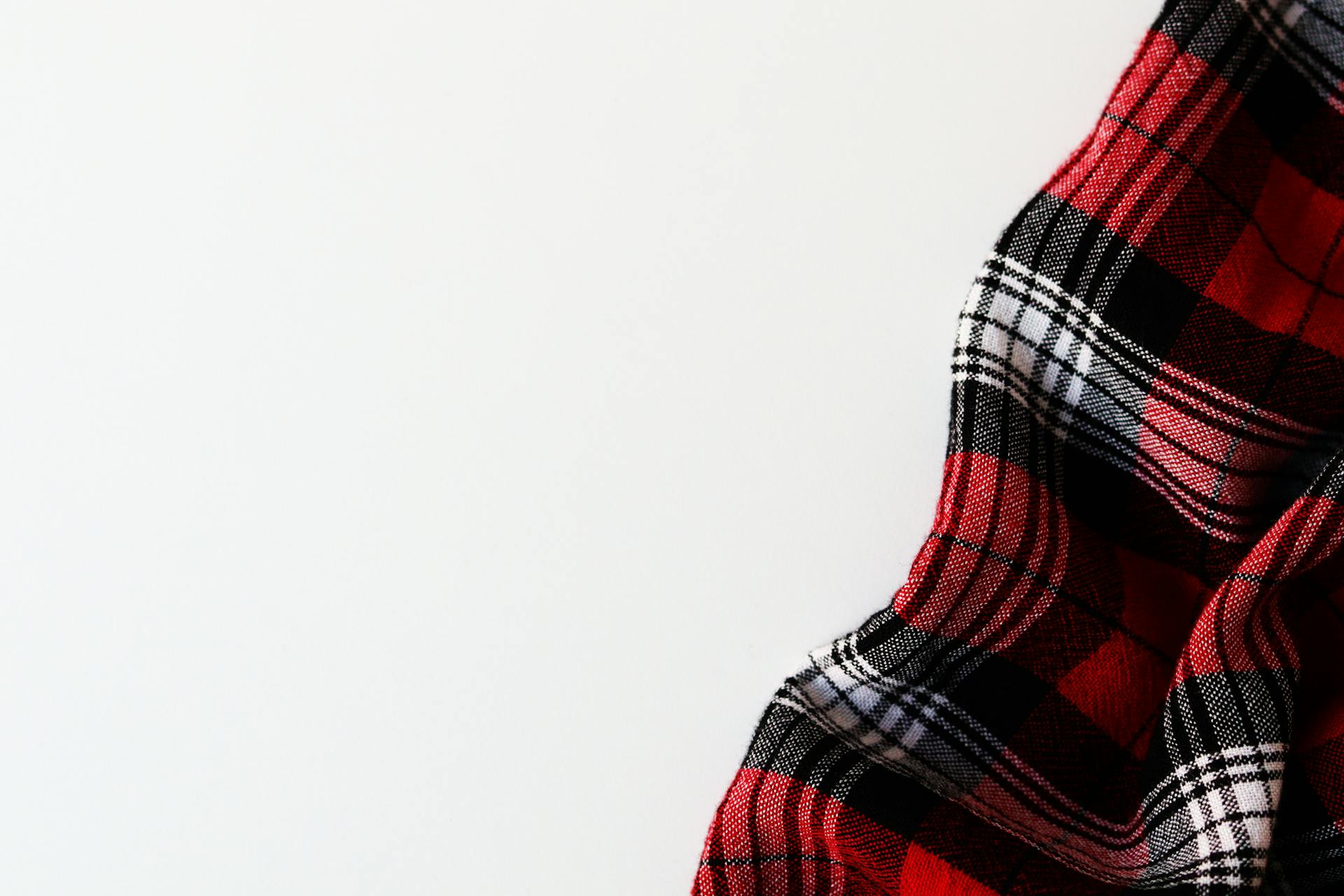 Close-up of red plaid flannel fabric on a white background, showcasing texture and pattern.