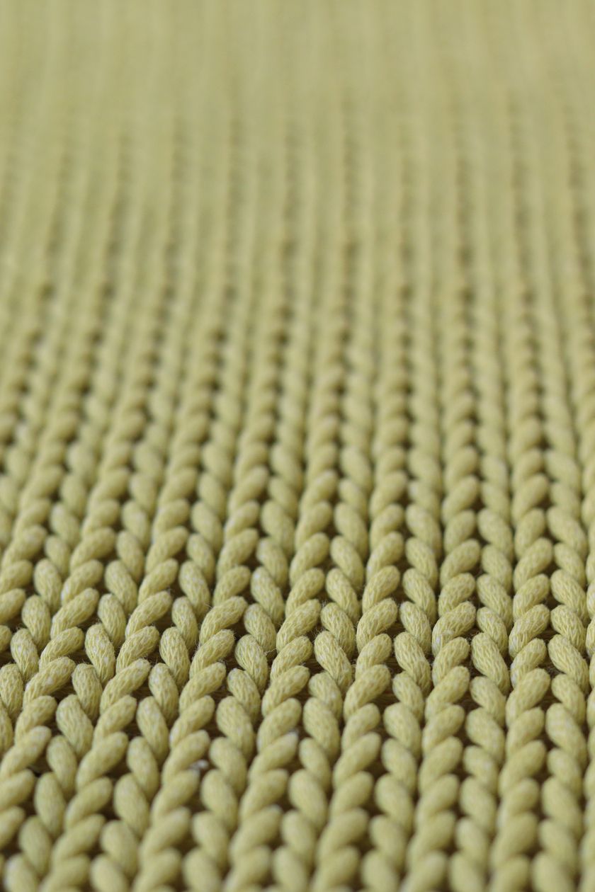 Macro close-up of a coarse olive knit, thick rounded loops in even rows filling the frame.