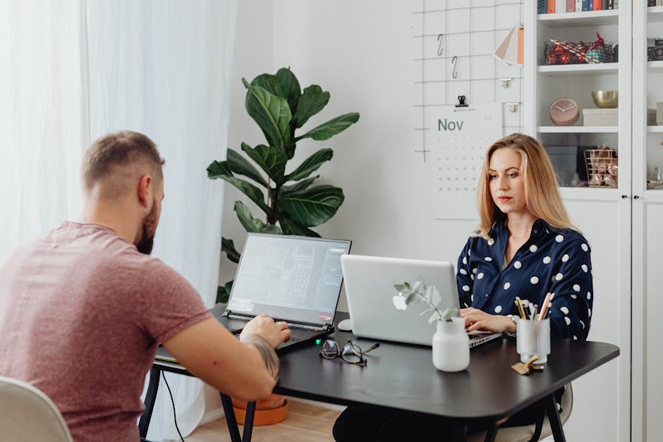 Does NordVPN Actually Block Malware Ads and Trackers? A man and woman collaborate at a desk with laptops, promoting teamwork in a modern office.