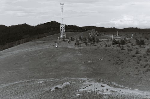 Electricity tower on hill near lonely faceless person