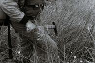 Anonymous male geologist with hammer and expedition equipment in field