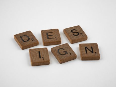 Wooden Scrabble tiles spelling the word 'DESIGN' on a white background.