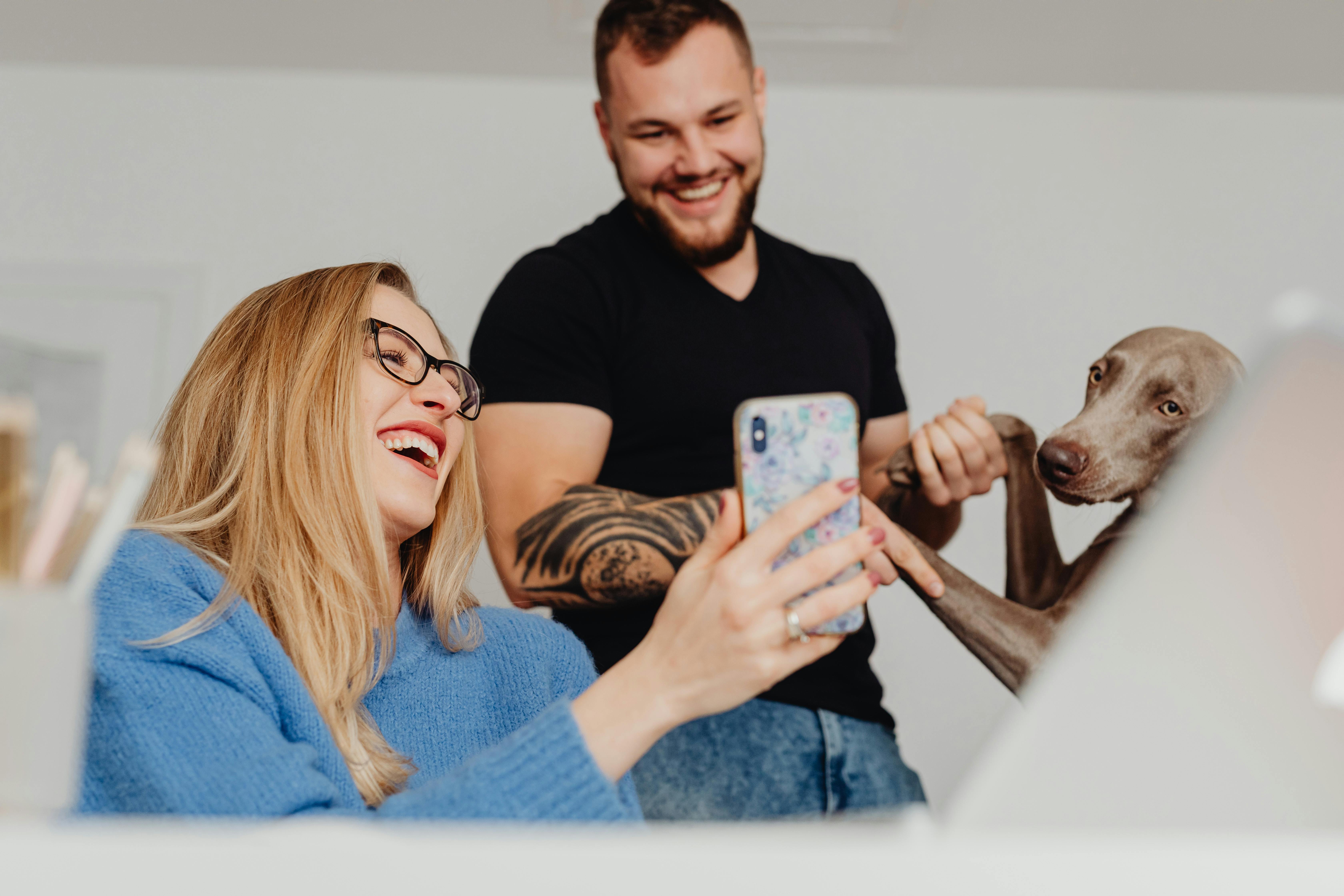 Cheerful couple taking a fun selfie with their adorable dog indoors.