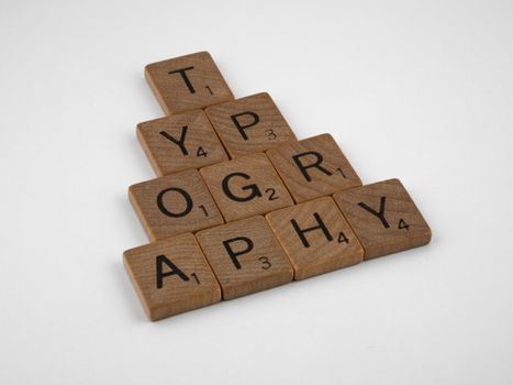 Close-up of wooden Scrabble tiles spelling 'Typography' on a white background.