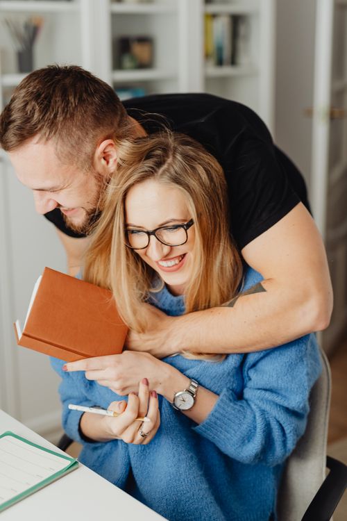 Free A joyful couple embracing while working at home, enhancing work-life balance. Stock Photo