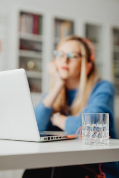 Focused woman at her desk using a laptop with headphones, embodying modern work from home style.