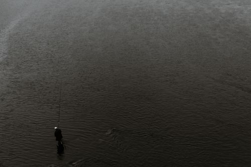 Free Drone view black and white of unrecognizable person standing in river and fishing with fishing rod Stock Photo