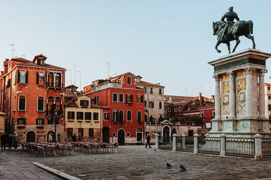 A historic square in Venice featuring an equestrian statue and colorful facades at sunset.