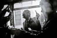 Black and white of woman near crop male passenger using ticket puncher in retro vehicle during trip