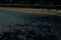 Pale white abstract mandala ornament painted on asphalt road in rural area in daylight