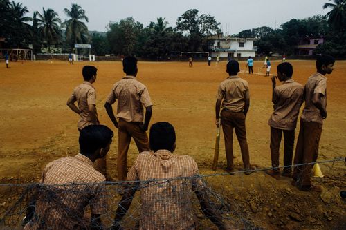 Free Group of anonymous African children in school uniforms playing cricket on sports ground in rural village Stock Photo