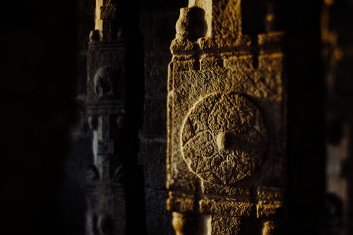 Rusted metal details of aged indigenous building with carved mythological ornamental patterns in evening sunlight