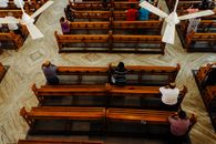 From above of calm people sitting on wooden benches and praying in cathedral