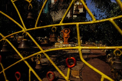 Yellow fence from iron in front of yard with Buddha statue and stones