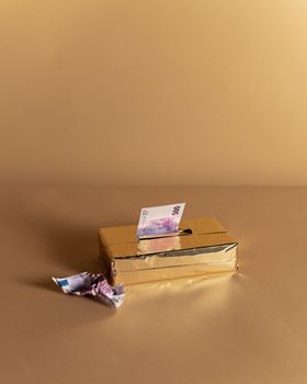 米色背景上，一个装有欧元纸币的金色盒子象征着财富与奢侈
