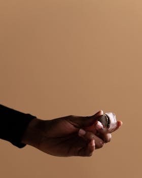 A symbolic photo of a hand holding a coin inside an ice cube, against a beige backdrop.