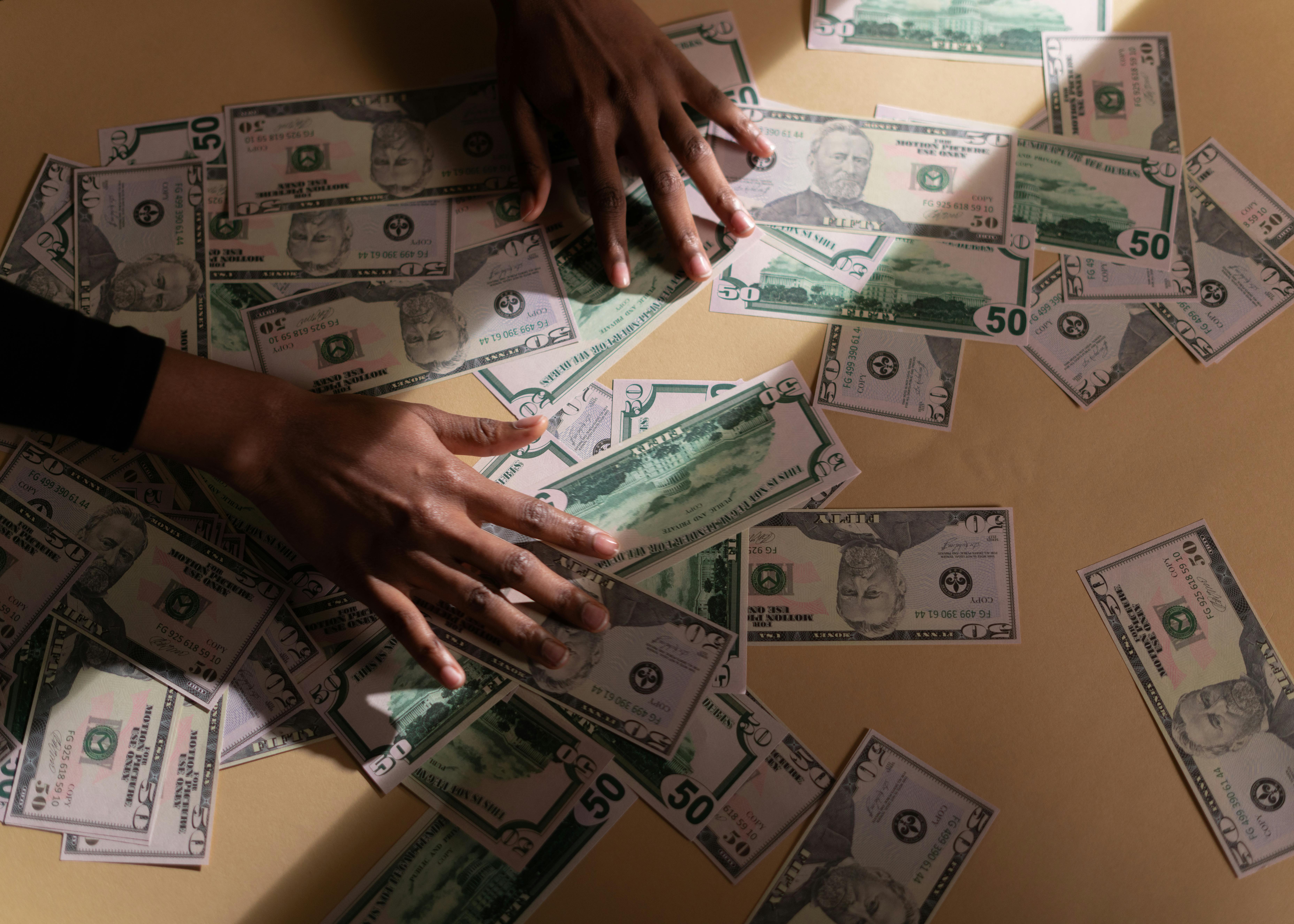 hands on table with dollar bills