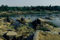 From above picturesque view of calm water of river with massive rocks and aged stone structure on bank