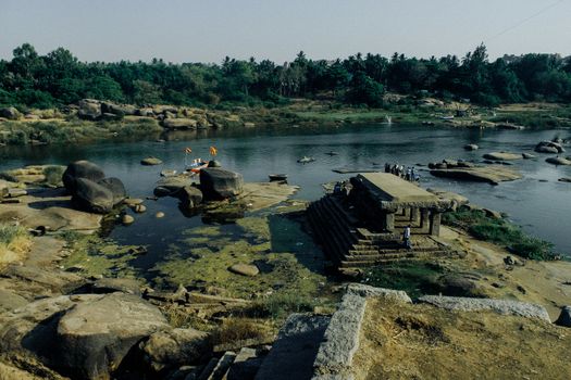 From above picturesque view of calm water of river with massive rocks and aged stone structure on bank