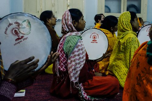 Free Side view of group of young Indian females in traditional garments sitting in room with pandeiro drums and looking away Stock Photo