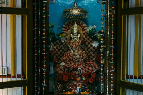 Free Colourful statue of Indian traditional god sculpture on throne with bright clothes decorated with flowers in traditional oriental altar for home prays and meditations Stock Photo