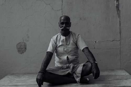 Free Black and white of serious Indian male with mustache looking at camera while sitting on wooden floor in Lotus pose Stock Photo