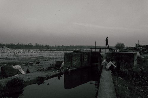 Free Black and white of faceless person walking alone on abandoned old place near river Stock Photo