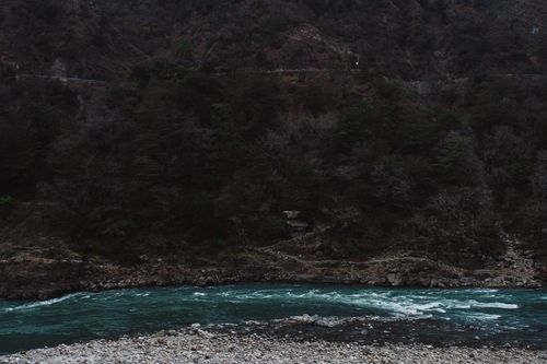 Free Picturesque view of river with fast stream flowing through rough rocky formations covered with green forest Stock Photo