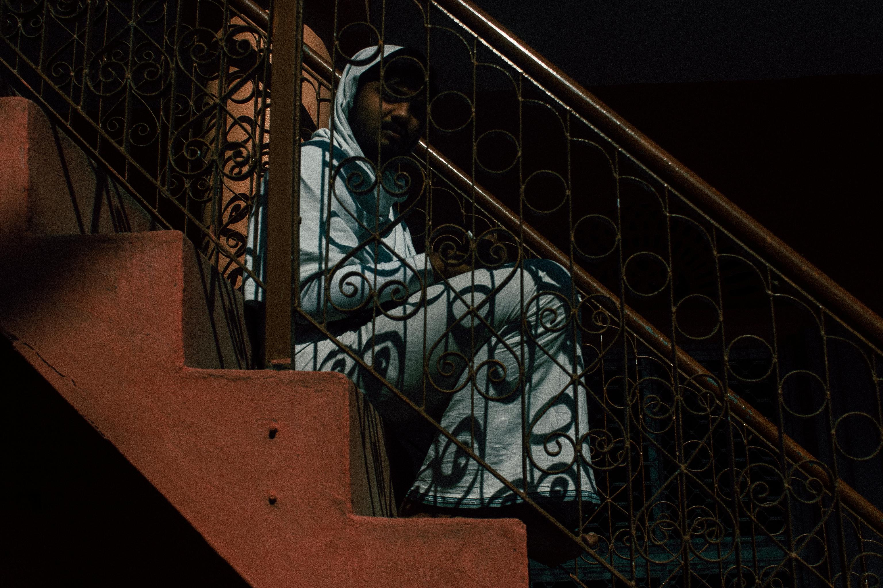 pensive ethnic man sitting on stairs at home