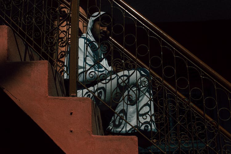 Pensive Ethnic Man Sitting On Stairs At Home