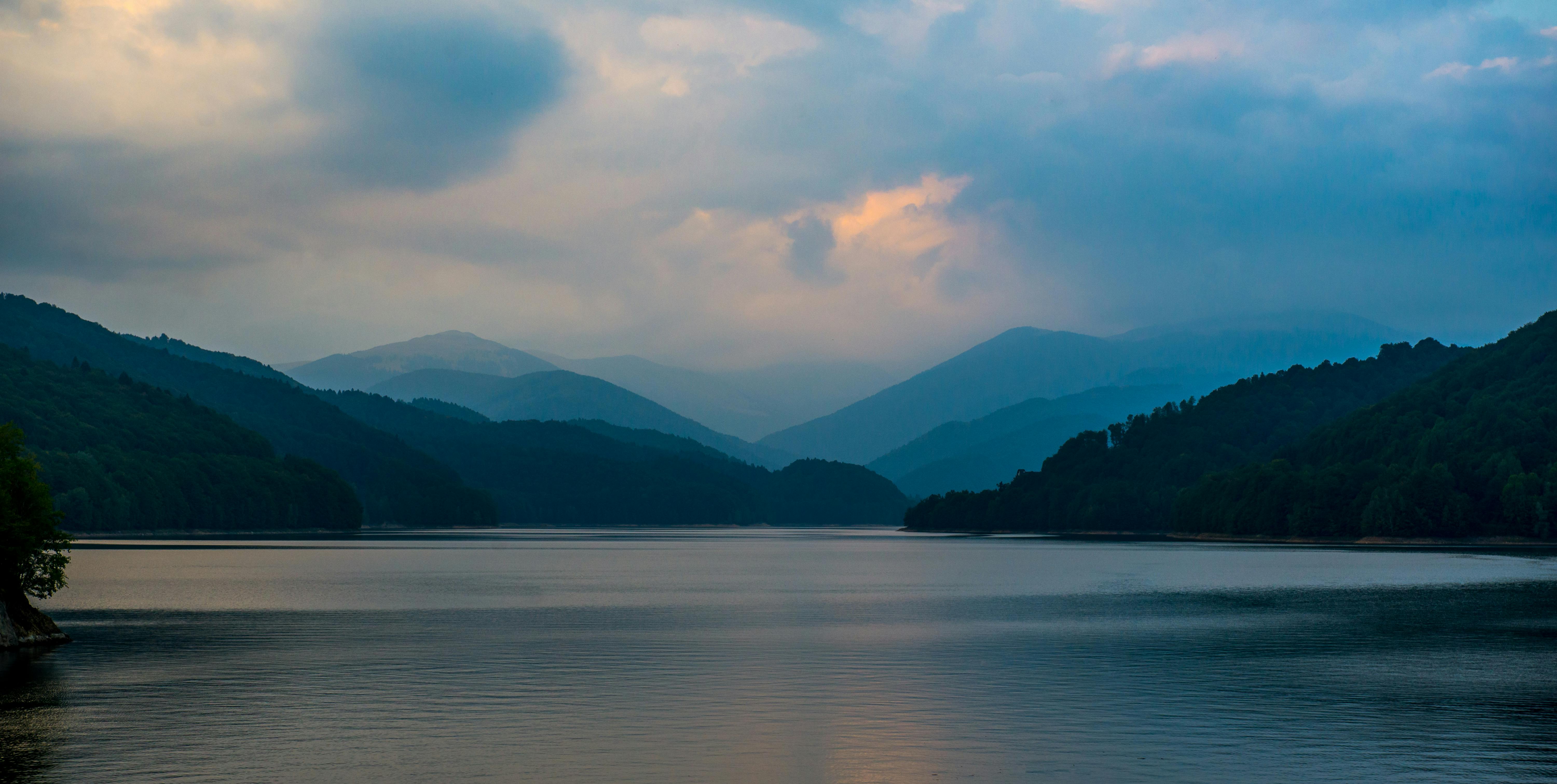 Serene view of a mountain lake at twilight in Curtea de Argeș, Romania.