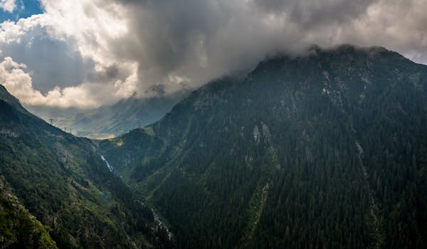 Panoramic view of the Făgăraș Mountains under dramatic cloud cover in Romania. Stunning natural scenery.