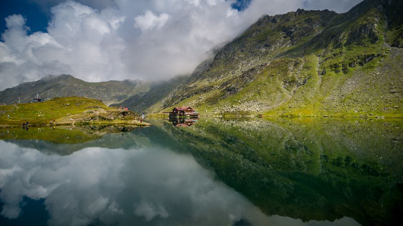 Lacul Bâlea oglindind Munții Făgăraș, cu reflexii pe apă
