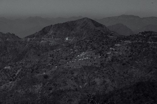 Free Black and white of picturesque scenery of mountains covered with plants and small village located in highland Stock Photo