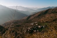 Spectacular view of empty land with small settlement surrounded by hills on day with good weather