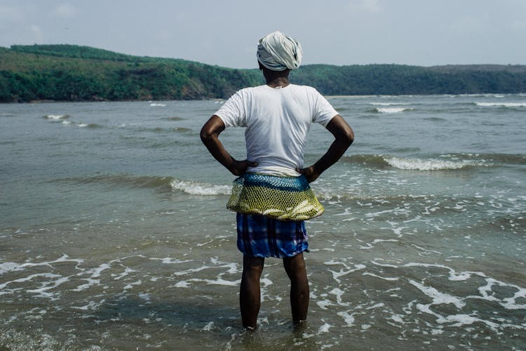 Ethnic Male Fisher Standing In Water Of Waving River