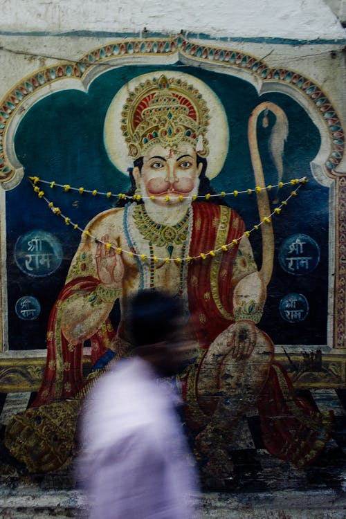 Indian man walking along artwork of Hinduism deity