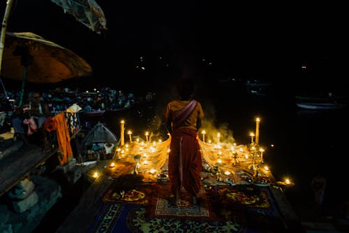 Indian woman praying with burning candles at night