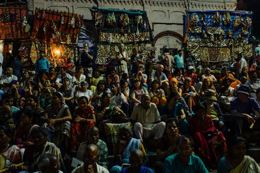 A lively festival crowd gathers in India, enjoying a night event with colorful decorations.