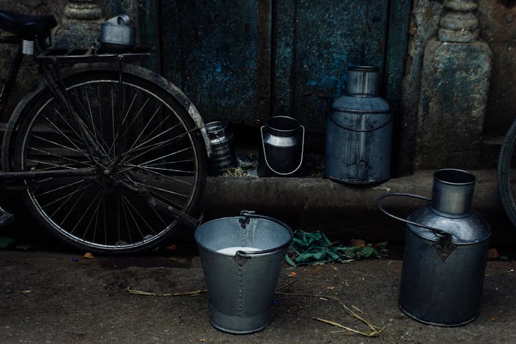 Tin Cans And Bucket Of Milk Next To Bike