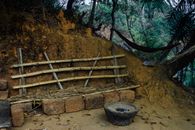 Stone fireplace for cooking near seats for tribal inhabitants made of bamboo and granite in jungle